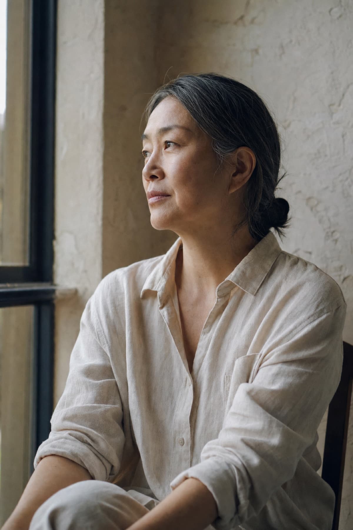 A woman in her fifties by a tall window in morning light
